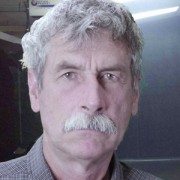 Grumpy-looking man with bushy gray hair and mustache